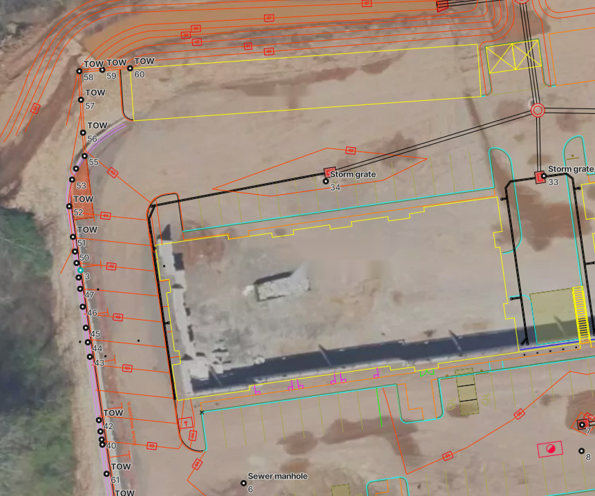 Stakeout points set from approved plans and shown on the orthomosaic, with a run of top-of-wall points, located storm structures, and building footprints
