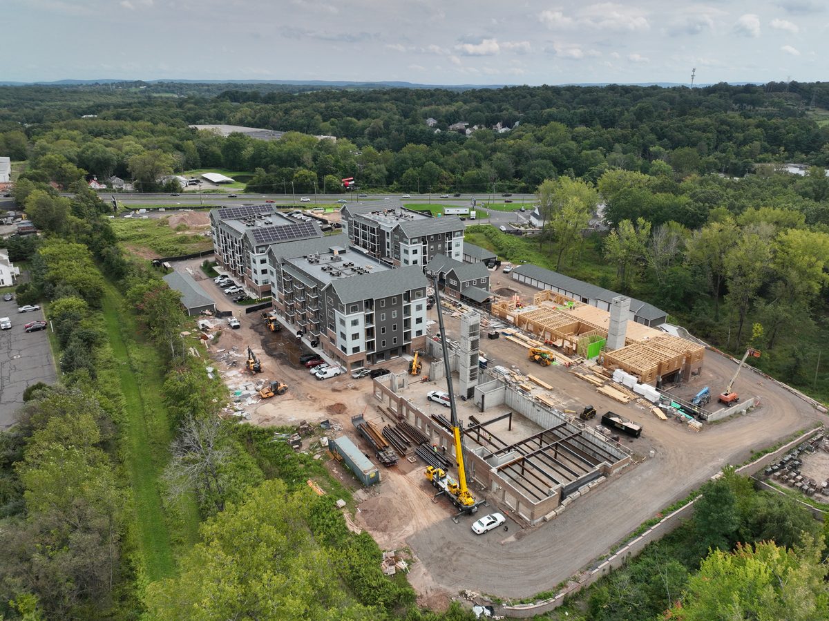 Aerial view of a multifamily site with a tower crane in place and the podium deck under construction